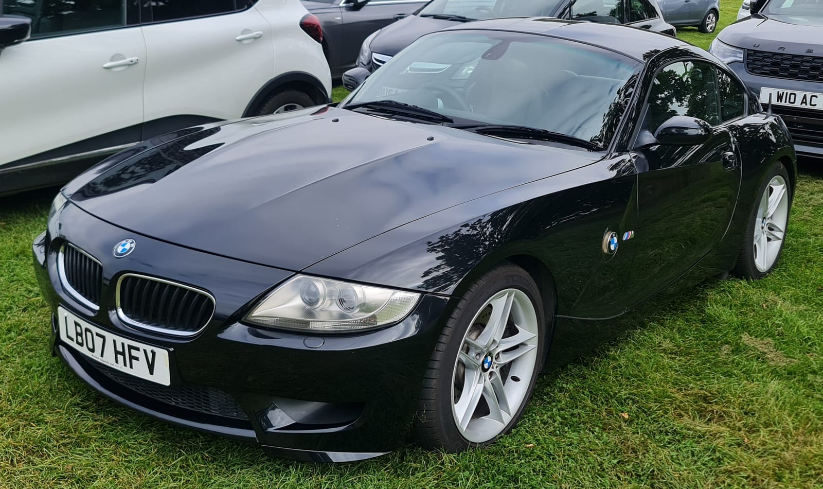 Black BMW Z4 M Coupe parked on grass, front three-quarter view